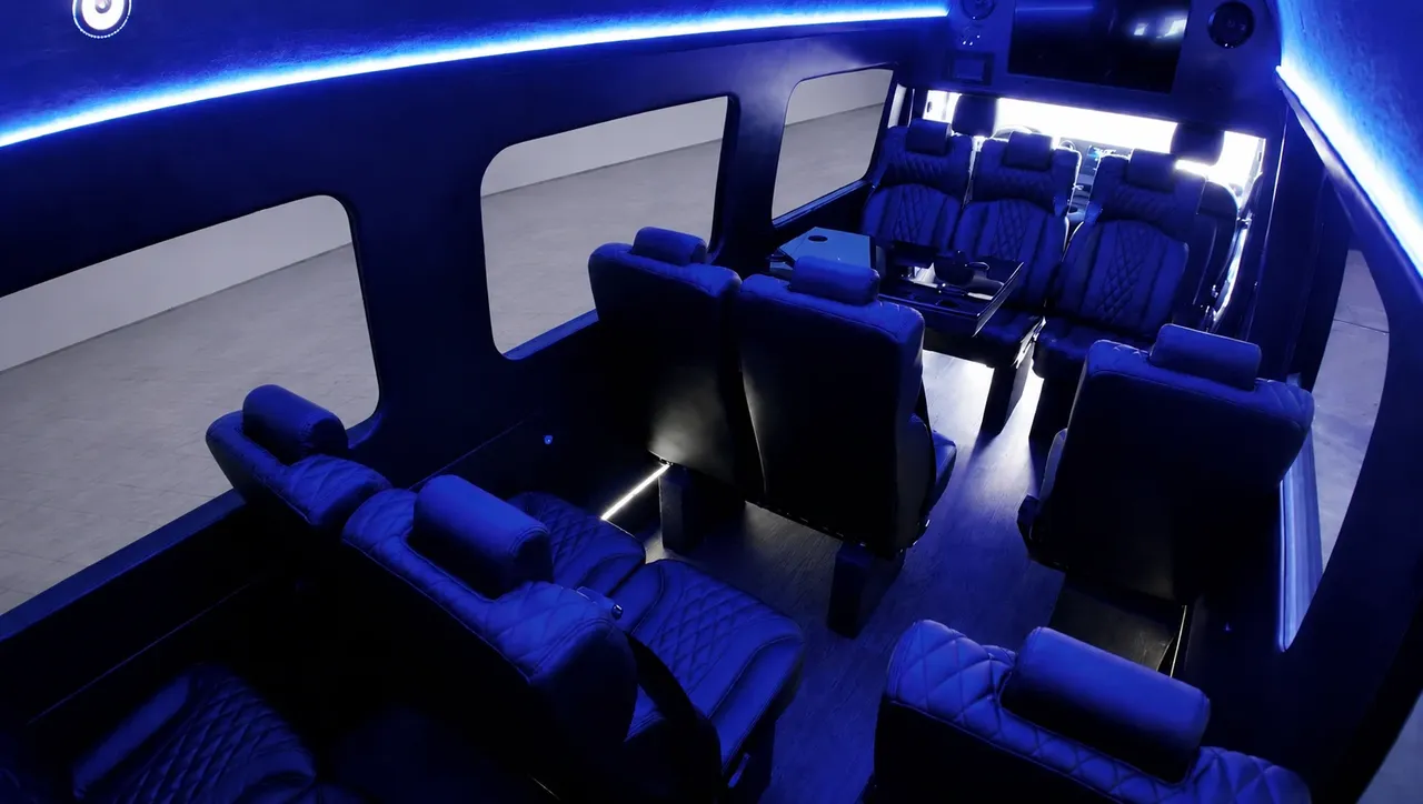 Black Luxury Sprinter Shuttle Van interior with captain's chairs, passenger tables and LED accent lighting for winery tour transport in Woodland Hills, CA