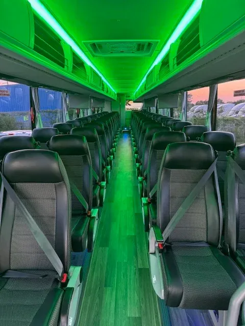 56 Passenger Charter Bus interior with LED ceiling lighting, passenger seat belts and overhead parcel racks for charter bus rental in Ocoee, FL