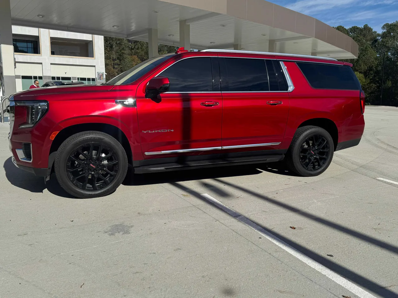 Red GMC Yukon XL exterior with tinted windows and running boards for airport transfers Red GMC Yukon XL exterior with tinted windows and running boards for airport transfers