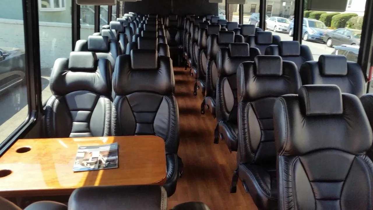 36 Passenger Mini Coach interior with passenger tables and wood-look flooring for minibus rental