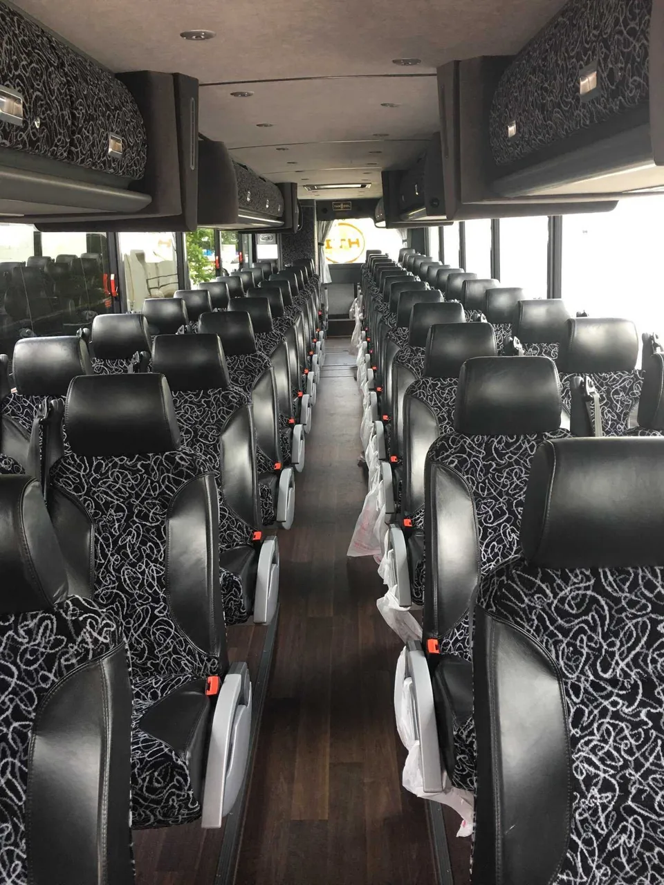 56 Passenger Motor Coach interior with passenger seat belts and overhead parcel racks for charter bus rental in Curwensville, PA