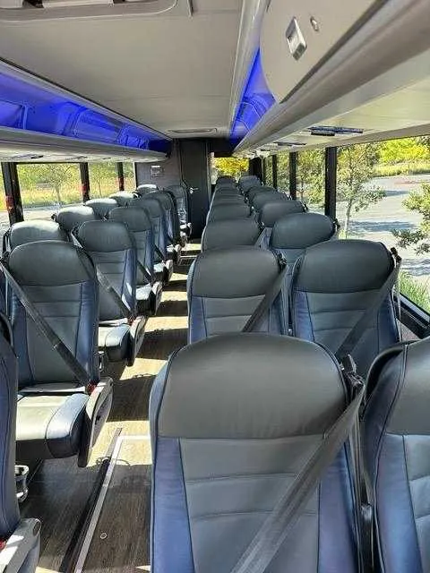 36 Passenger Motorcoach interior with LED accent lighting and overhead parcel racks for charter bus rental in Daly City, CA