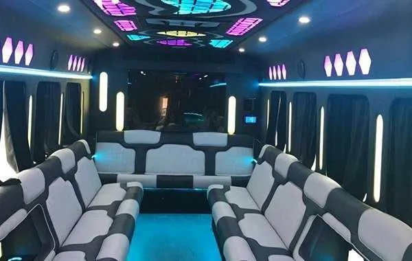 Party Bus White interior with perimeter lounge seating, window shades and LED accent lighting for party bus rental