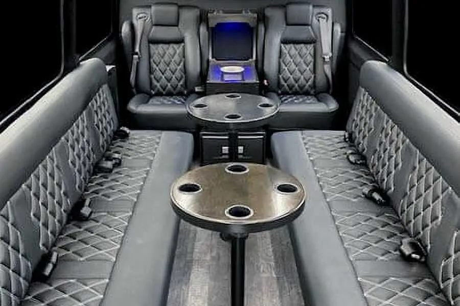 12 Passenger Sprinter Van interior with perimeter lounge seating, captain's chairs and passenger tables for party bus rental