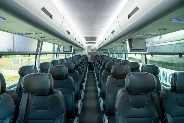 ADA Coach interior with LED ceiling lighting, TV screens and overhead parcel racks for charter bus rental in Agua Dulce, TX