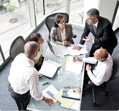 Rental coordinators comparing vehicle availability and quotes around a meeting table Rental coordinators comparing vehicle availability and quotes around a meeting table