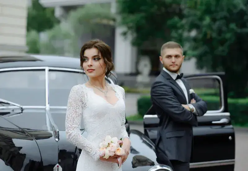 Bride and groom beside their wedding car